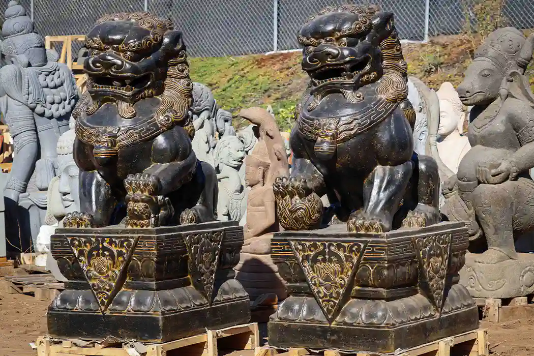 Large Foo Dog guardian sculptures hand-carved from saffron lava stone, symbolizing protection and strength.